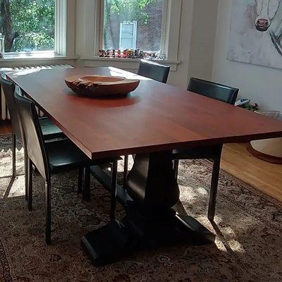 A big cherry dining table on beefy black pedestals.