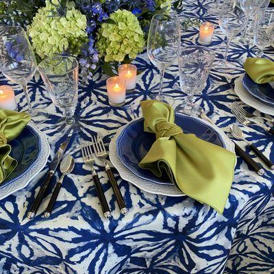 Navy Shibori Tablecloth with Capri Lamour Satin Napkins and Lime Woven Napkin Rings. ⁠