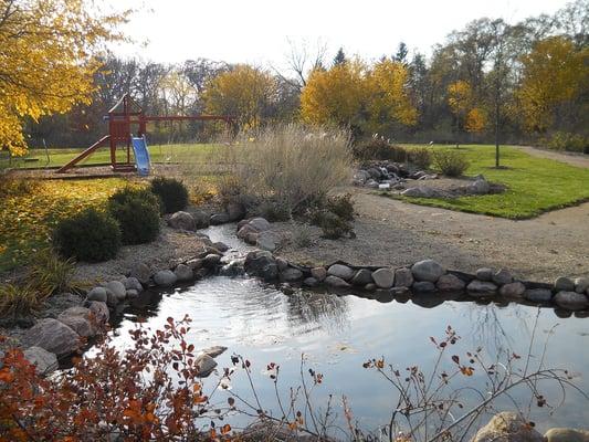 Serenity Pond and walking path at Elgin location with playground, sand volleyball court and basketball court