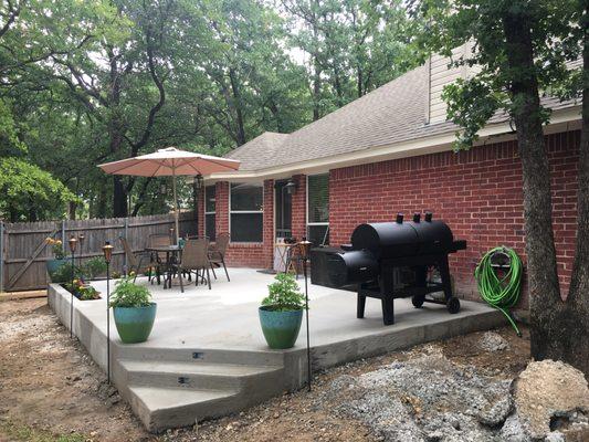 Concrete patio with steps and planter boxes in the backyard