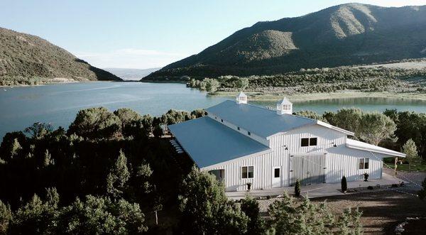 Aerial shot of Vista View Events, a white wedding barn in Colorado. This photo shares the venue overlooking Harvey Gap Reservoir.