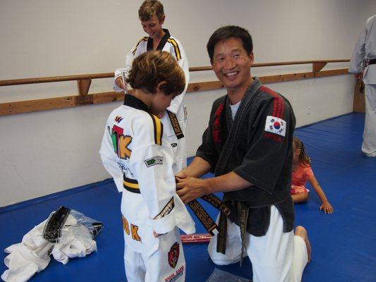 Master Kang is proud to award the Taekwondo Black Belt to one of his students.