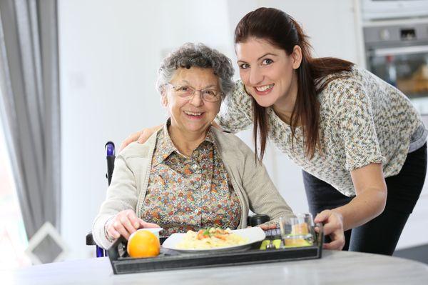 homecarer-preparing-lunch-for-elderly-woman