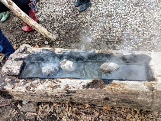 Old fashioned cooking: fired-hot stones in carved out log