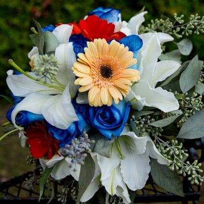 This Bridal Bouquet is designed with Blue Roses, White Lilies, Orange Gerbera  Daisy, Peach Gerbera and Greens (Seeded Ecu).