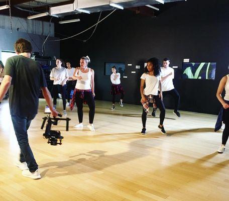 Class being filmed in the big studio, windows for parents and friends to watch from hallway.