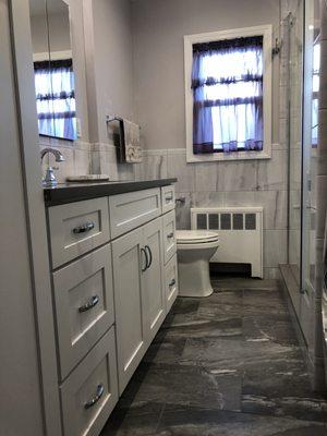 Grey bathroom with white vanity and linen closet.