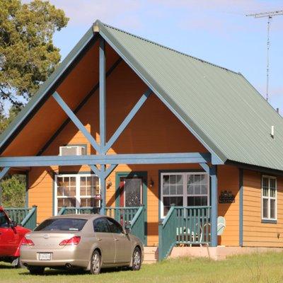 Bluebonnet Cabin is larger, backing up into the woods, facing a lovely meadow with a large pond with pier.  Sunsets are perfectly reflected.