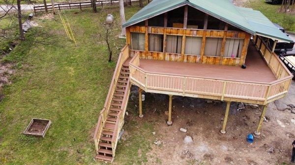 Deck wrapping halfway around the house with a portion of it covered.