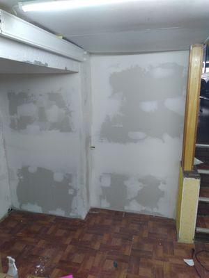 Removal of popcorn wall followed by installation of sheetrock drywall.