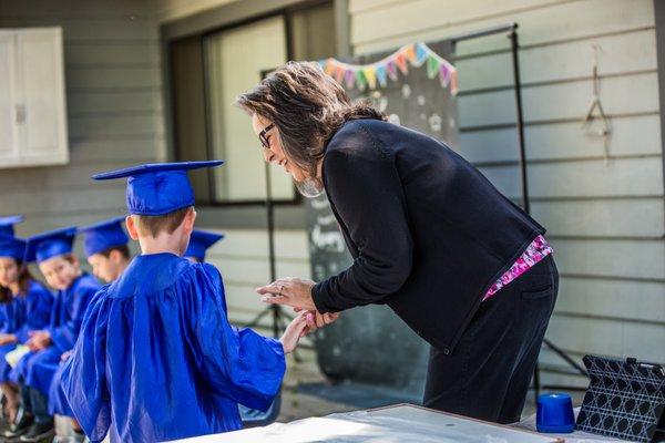 Our director, Ms. Anna, handing a  graduating student his diploma.