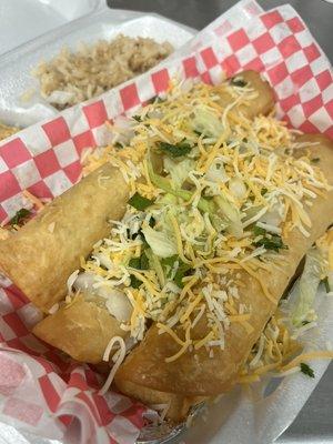 Shredded chicken flautas topped with lettuce and cheese