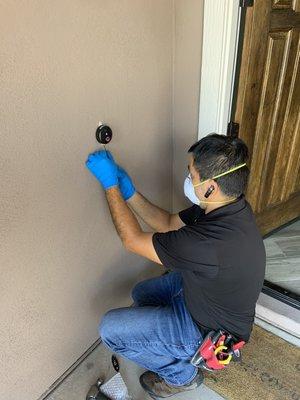 Doorbell camera installation with protective mask and gloves.