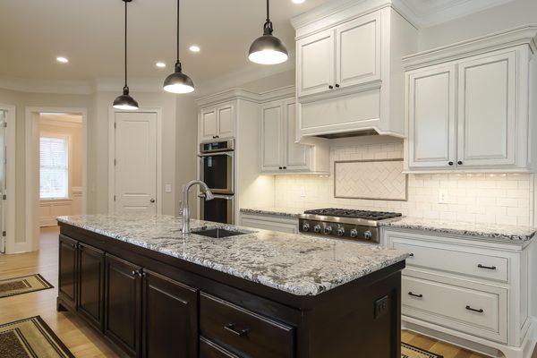 This gorgeous kitchen features a large center island with custom black cabinets, granite countertops, and an undermount prep ...