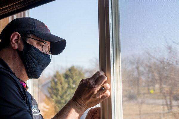 George Ramirez inspecting vinyl windows that are to be replaced by Andersen windows.