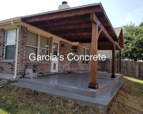 Patio cover with side peak and flat roof.  Regular brush finish concrete with step.