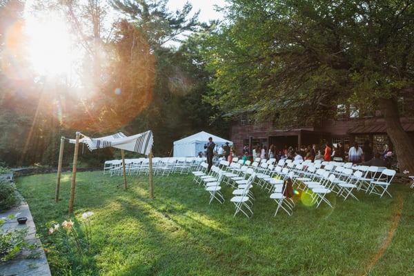 Bamboo chuppah, white resin chairs, and tent at the Brydcliffe Guild Barn (Woodstock).