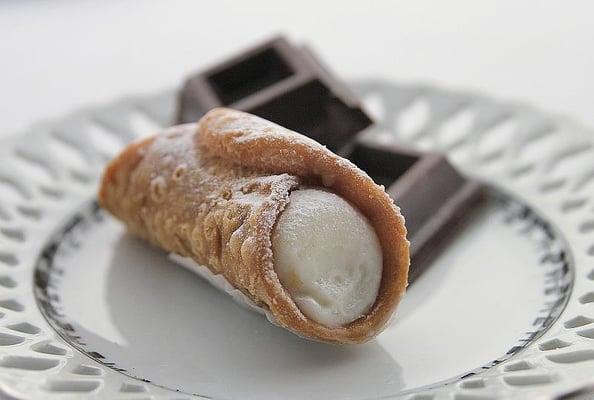 Cannoli, consisting of a tube-shaped shell of fried pastry dough, filled with sweet, creamy filling of ricotta cheese.