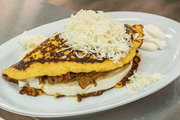 Cachapa filled with "Queso de Mano" and Shredded Beef, topped with Santa Barbara Cheese and Nata on the side