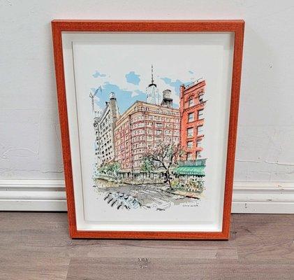 An architectural watercolor painting of a few buildings. Artwork is floating to display raw edges. Paired with a red orange frame.