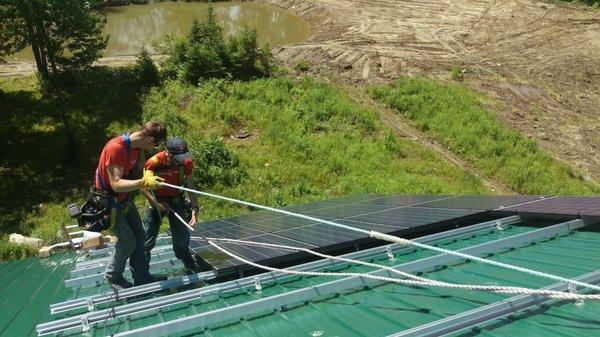 Sundog Solar installers putting solar panels on a metal roof near Rockport, Maine