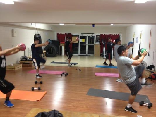 Bootcamp group exercise, total body session.  Working the shoulders with the medicine ball and core as they add the high knees.