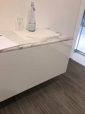 Granite countertop cabinet in the meeting room. Also sleek water carafe.