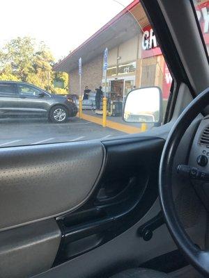 Two employees one not wearing a mask several customers walking out the door and into the grocery store not wearing masks