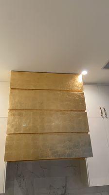 Final results on these beautiful kitchen hood . Gold leaves and varnish clear to seal it and protect from heat .