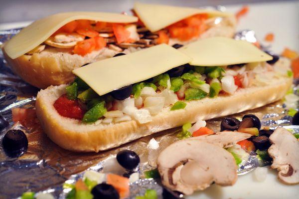 Fresh Vegetables Being Added To A Sub.