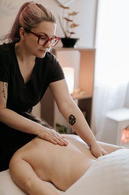 A woman receives massage therapy to her back.