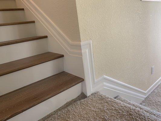 Wood treads, white risers, stair skirts, and baseboard installation by Refined Installations