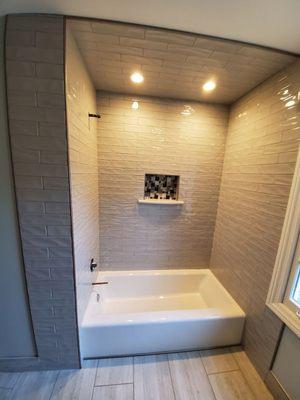 This is a bath tub with tile walls.