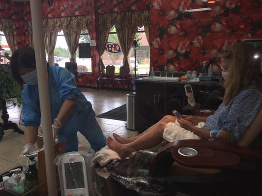 Pedicure spa with plexiglass barriers between stations, all employees with appropriate PPE