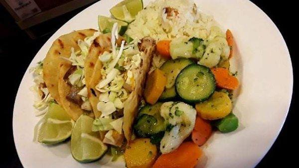 Fish Tacos with a cilantro cream sauce sautéed vegetables and seasoned rice