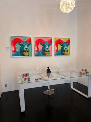 Back wall of the gallery showcasing 3 large archival art prints of a local Long Horned Sheep drinking a martini.