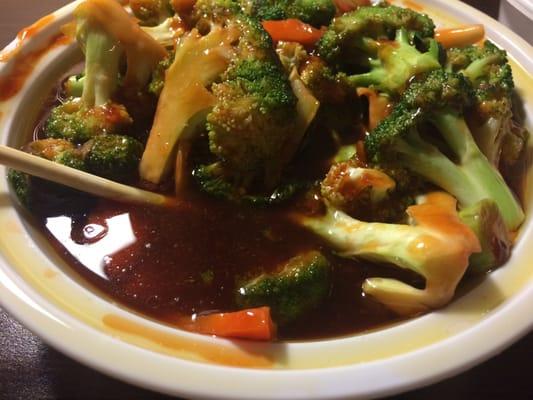 Broccoli with garlic sauce sitting in a bowl full of oil.