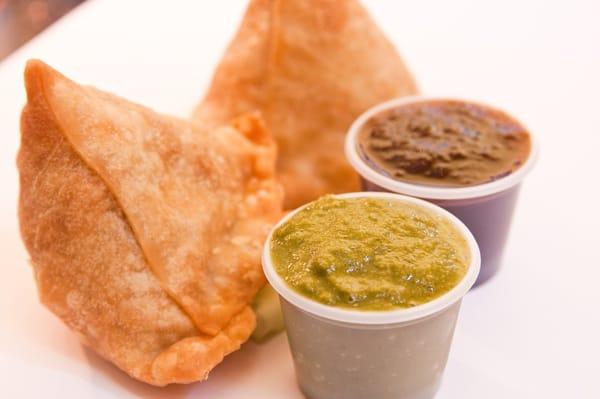 Samosas with mint and cilantro chutney and tamarind chutney.