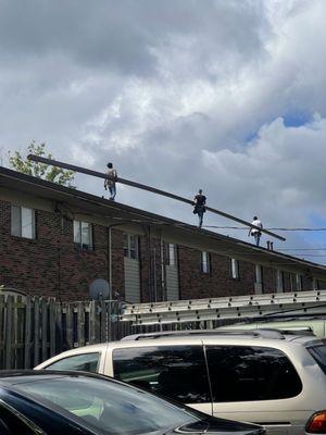 Installing a long gutter on an apartment building.