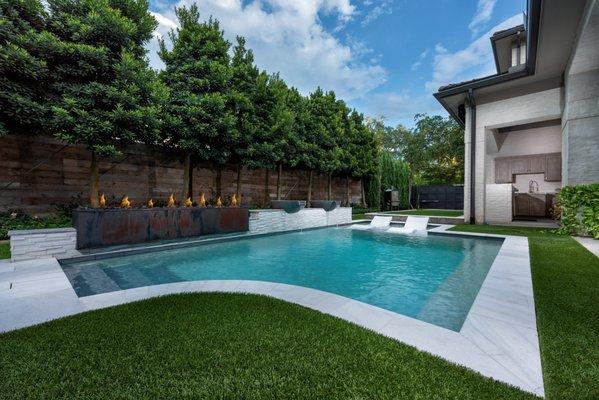 Gorgeous geometric custom pool with a breathtaking raised wall featuring water bowls a fire wall.