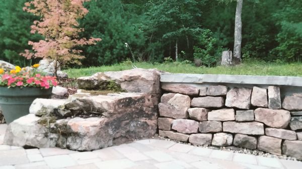 Drystack retaining wall with mortared capstone and boulder end.