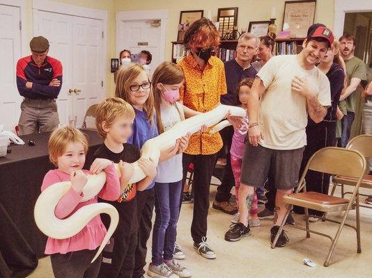 Group of kids holding a very long, large snake thanks to New England Reptile Shows