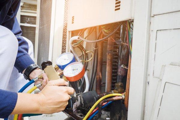 Checking refrigerant levels in an air conditioner.