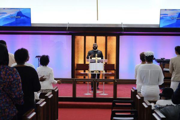 Pastor Smith and the congregation praising God during service.