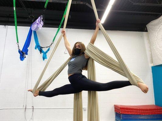 A student performs an advanced front split on the aerial silks