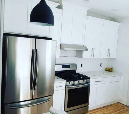 Kitchen renovation with stainless steel appliances and all white cabinets and counter tops.