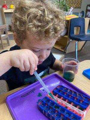 Working on our fine motor motor skill, pinching with pipets and poppers.