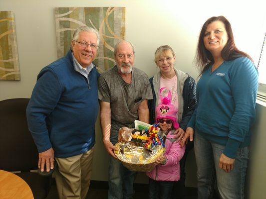 Happy New Home Owners, Bob and Tammy and their grand daughter and loan officer.  Showing of the  house warming basket from their Agent.