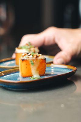 Seared butternut squash with torched Brie cheese, tarragon, and chips nuts.