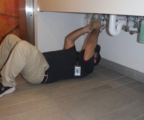 Day porter refilling soap dispenser at a commercial building.